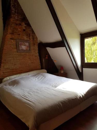 un lit dans une chambre avec un mur de briques dans l'établissement chaumière familiale weekend & vacances paisible, à Saint-Philbert-sur-Risle