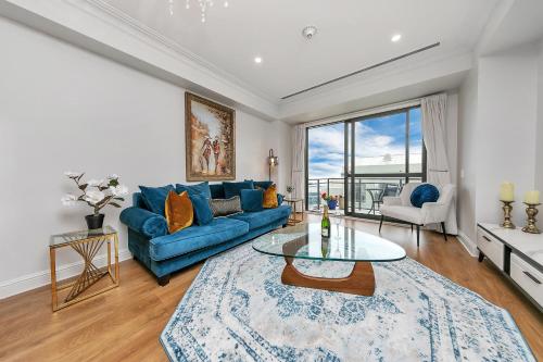 a living room with a blue couch and a table at Corporate Gem + Rooftop Pool & Spa in Auckland
