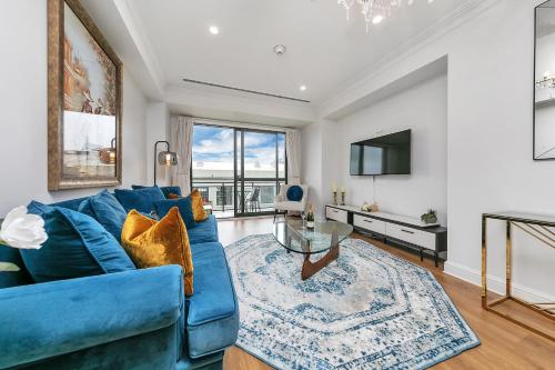 a living room with a blue couch and a tv at Corporate Gem + Rooftop Pool & Spa in Auckland