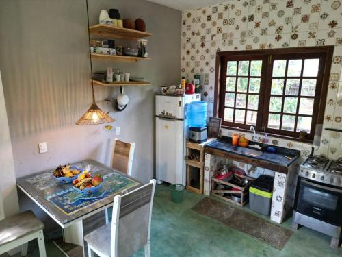 uma cozinha com uma mesa e um frigorífico em Madeirascamping na Ilha de Boipeba