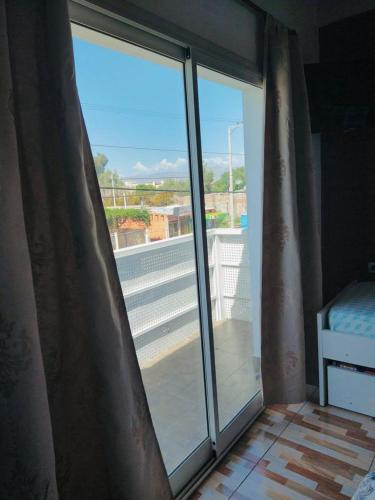 Cette chambre dispose d'une porte coulissante en verre s'ouvrant sur un balcon. dans l'établissement Departamento monoambiente para 4 personas, à Rivadavia