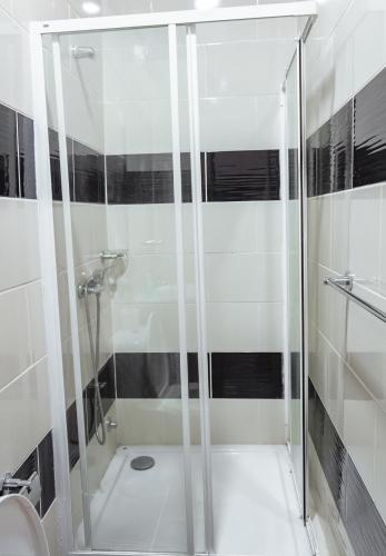 a shower with a glass door in a bathroom at Baig's Guest House in São Tomé