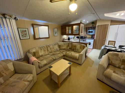 a living room with couches and a table at 7 Rannoch Row, lovely holiday static caravan for dogs & their owners. in Forfar