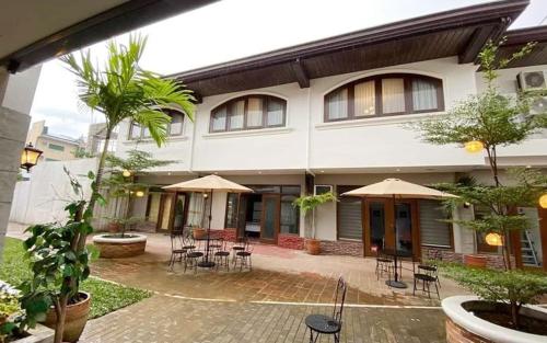 un bâtiment avec des chaises, des tables et des parasols dans l'établissement Solano Hotel & Resort At Casa Ysabel, à Lipa