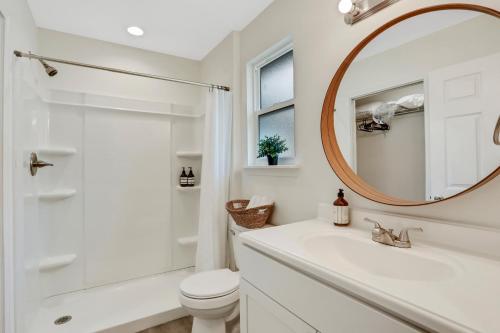 a white bathroom with a toilet and a mirror at Modern home with garage near town in Saint Augustine