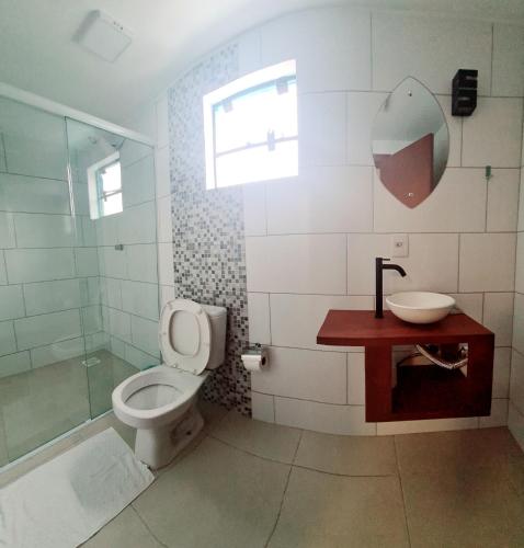 a bathroom with a toilet and a sink and a shower at Pousada Doce Mar in Guarda do Embaú