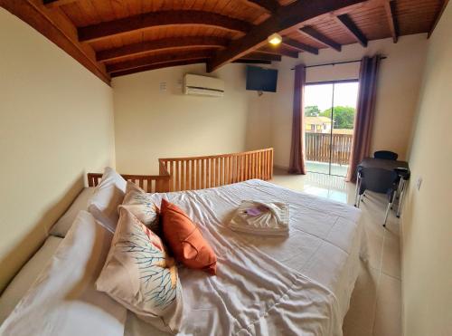 a bedroom with a bed with white sheets and pillows at Pousada Doce Mar in Guarda do Embaú