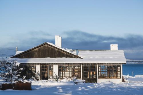 a building with a snow covered roof in the snow at Bories - Boutique Guest House in Puerto Natales