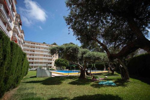 einem Park mit Bäumen, einem Pool und einem Gebäude in der Unterkunft PISO Reformado Moderno Piscina y Jardín! in Salou