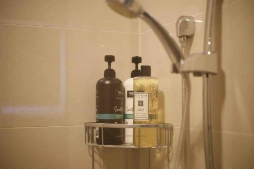a bathroom with three bottles of soap and a shower at Perfectly modern living home in Burwood in Burwood
