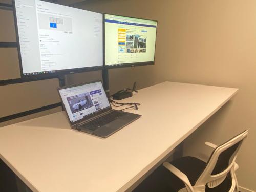 a laptop computer sitting on a desk with two monitors at Hamilton Hospital Retreat - 2 Bedroom Townhouse Modern Warm Quiet in Hamilton