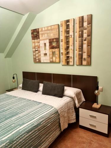 1 dormitorio con 1 cama y 3 cuadros en la pared en Atico das Barxas, en Moaña