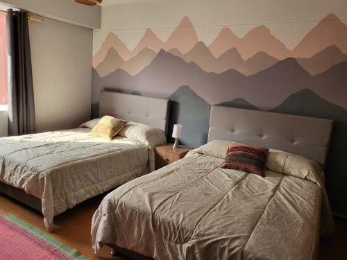 two beds in a bedroom with mountains painted on the wall at Alojamiento San Francisco - Apartamentos y habitaciones in Lima