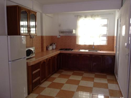 a kitchen with wooden cabinets and a white refrigerator at Ebrahim Flats - Grand Baie Beach in Grand Baie
