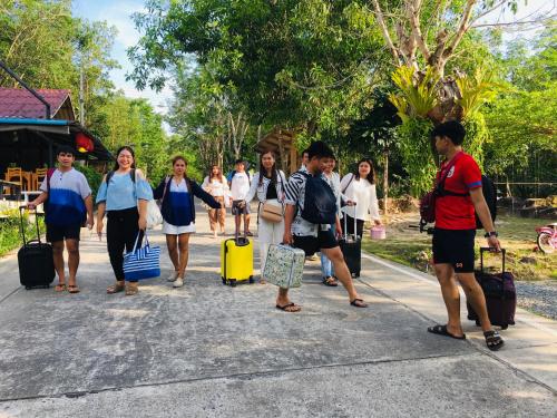 a group of people walking down a road with luggage at Baan Sangchan in Ko Kood