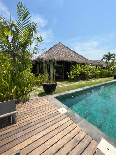a resort with a wooden deck and a swimming pool at La Reserva Villas Bali in Jimbaran