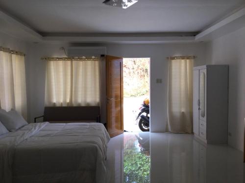 a bedroom with a bed and a window and a motorcycle at Gengs Apartment and Nmax Rentals in Dipolog