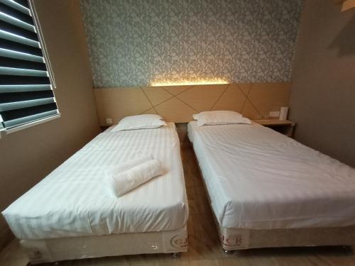 two twin beds in a room with a window at Dane & Shue Hotel Kok Lanas in Kota Bharu