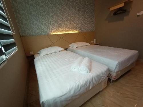two beds in a room with white sheets at Dane & Shue Hotel Kok Lanas in Kota Bharu