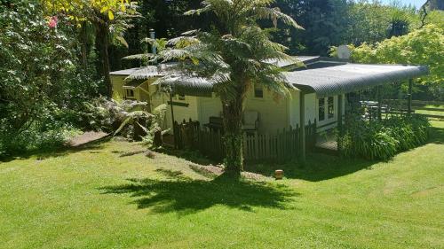 a small yellow house with a palm tree in the yard at Poihipi Farm Stay in Marotiri