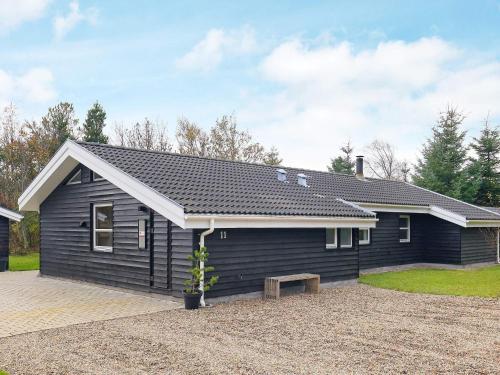 a black house with a bench in front of it at 10 person holiday home in Fjerritslev-By Traum in Fjerritslev