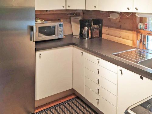 uma cozinha com armários brancos e um micro-ondas em Holiday home GJESDAL em Berge
