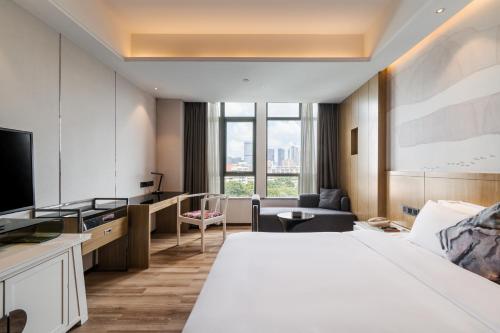 een hotelkamer met een bed en een televisie bij Paco Hotel Shuiyin Road Guangzhou-Canton Fair free shuttle bus in Guangzhou