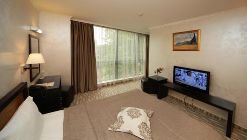 ein Hotelzimmer mit einem Bett und einem Flachbild-TV in der Unterkunft Efbet Hotel in Warna