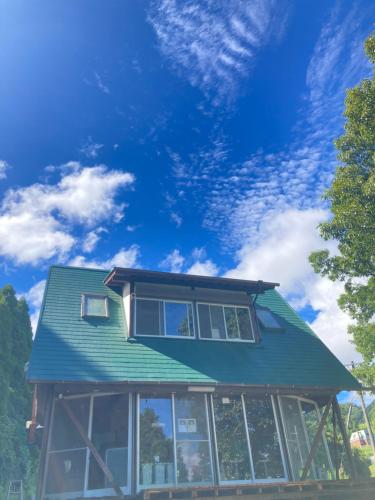 dom z zielonym dachem na górze w obiekcie Codona Hütte w mieście Minami Aso
