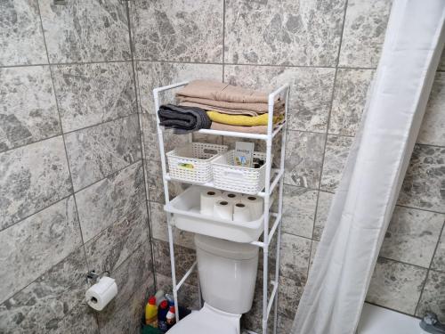 a bathroom with a toilet with a shelf above it at 2 Bed Flat North London in Edmonton