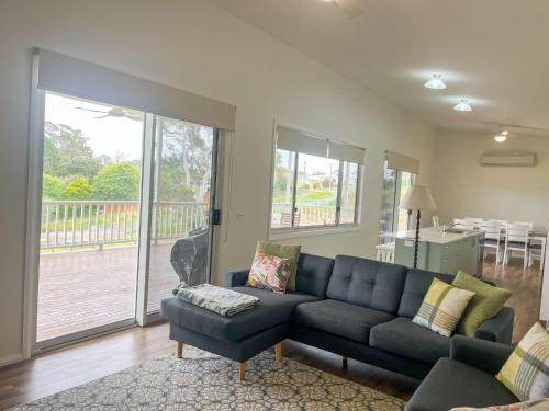 sala de estar con sofá negro y balcón en Eucalyptus House, en Timboon