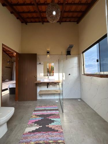y baño con ducha, aseo y alfombra. en Chalé Pousada Maná do Céu - São Jorge, en São Jorge