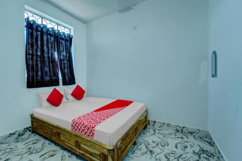 a bedroom with a bed with red pillows and a window at OYO Flagship Your Room & Guest House in Patna