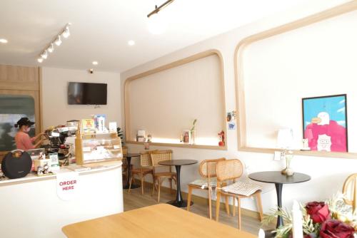 a coffee shop with a counter and tables and a person at NOW’S HOSTEL in Ban Chang