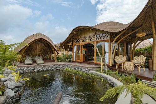 a house with a pond in front of it at Arapan Ubud Eco Villa in Ubud