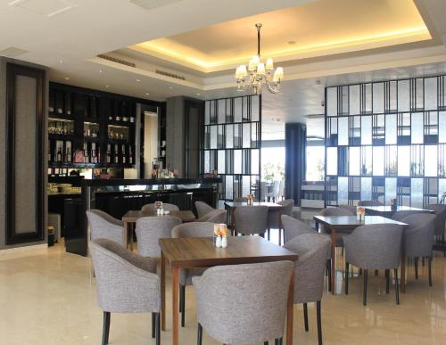 a restaurant with tables and chairs and a bar at Grand Mercure Solo Baru in Solo