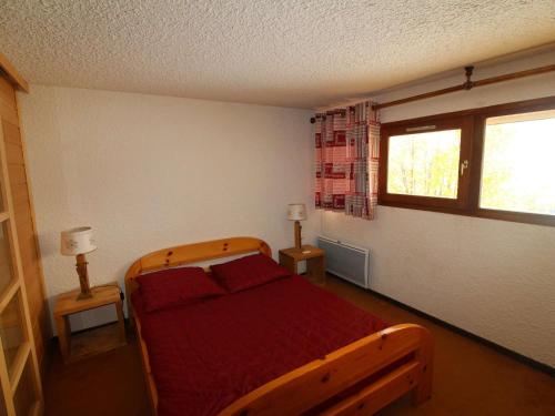 - une chambre avec un lit en bois avec des draps rouges et une fenêtre dans l'établissement Duplex 3 pièces cabine 8 pers, pied des pistes à Auris en Oisans - FR-1-297-337, à Auris