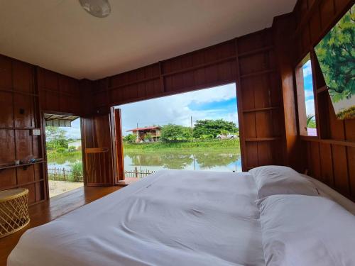 a large bed in a room with a large window at Ha Me Garden ฮามีการ์เด้น โฮมสเตย์ฝาง in Fang