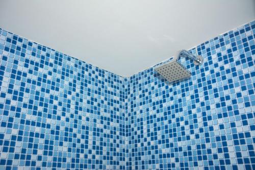 uma casa de banho com azulejos azuis e um chuveiro com uma cesta. em Araça flat 308 - Lateral Vista Jardim em Natal