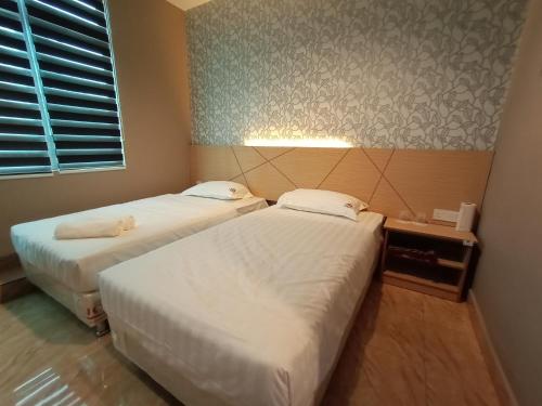 a room with two beds and a window at Dane & Shue Hotel Kok Lanas in Kota Bharu