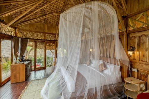 a bedroom with a bed with a mosquito net at Arapan Ubud Eco Villa in Ubud