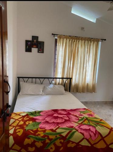 Un dormitorio con una cama con una manta de flores. en Chills homestay, en Kalpetta
