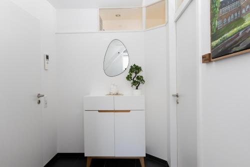 ein weißes Bad mit einem Wandspiegel in der Unterkunft Ruhe, Romantik und Ruhrgebiet vereint für Zwei in Schwerte