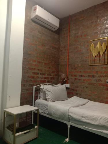 a bedroom with two beds and a brick wall at Dane & Shue Hotel Kok Lanas in Kota Bharu