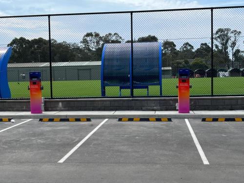 a parking lot with three parking meters in front of a fence at The Lodge, Blacktown - Sydney in Rooty Hill