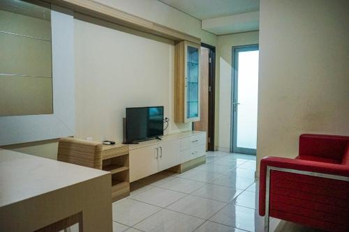 a living room with a television and a red chair at Apartemen Solo Center Point in Bonorejo