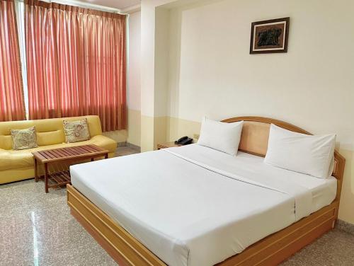 1 dormitorio con 1 cama grande y 1 sofá amarillo en โรงแรมเอสซีเรสซิเดนซ์ มุกดาหาร en Mukdahan