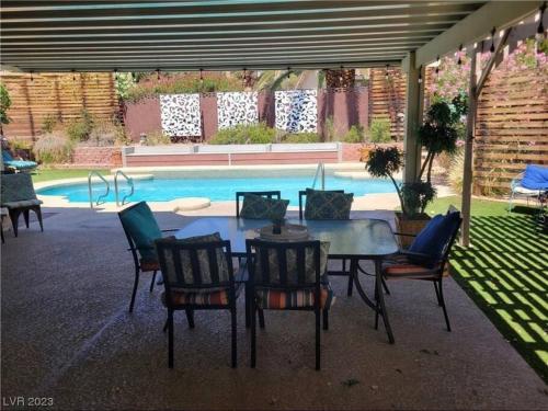 a patio with a table and chairs next to a pool at 4 miles to Strip / Big house with pool in Las Vegas
