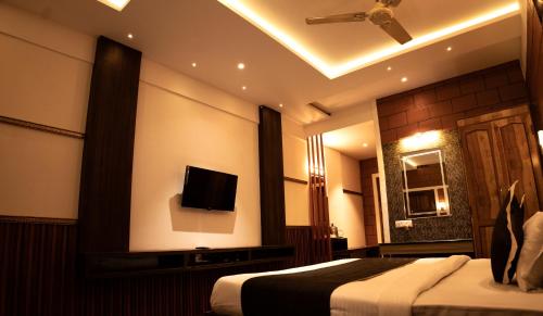 a hotel room with a bed and a tv on the wall at The Nest Inn Resort in Masinagudi