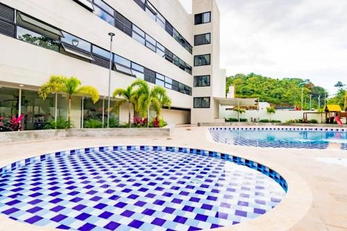 a swimming pool in front of a building at Elegante apartamento en condominio cerca del aeropuerto 